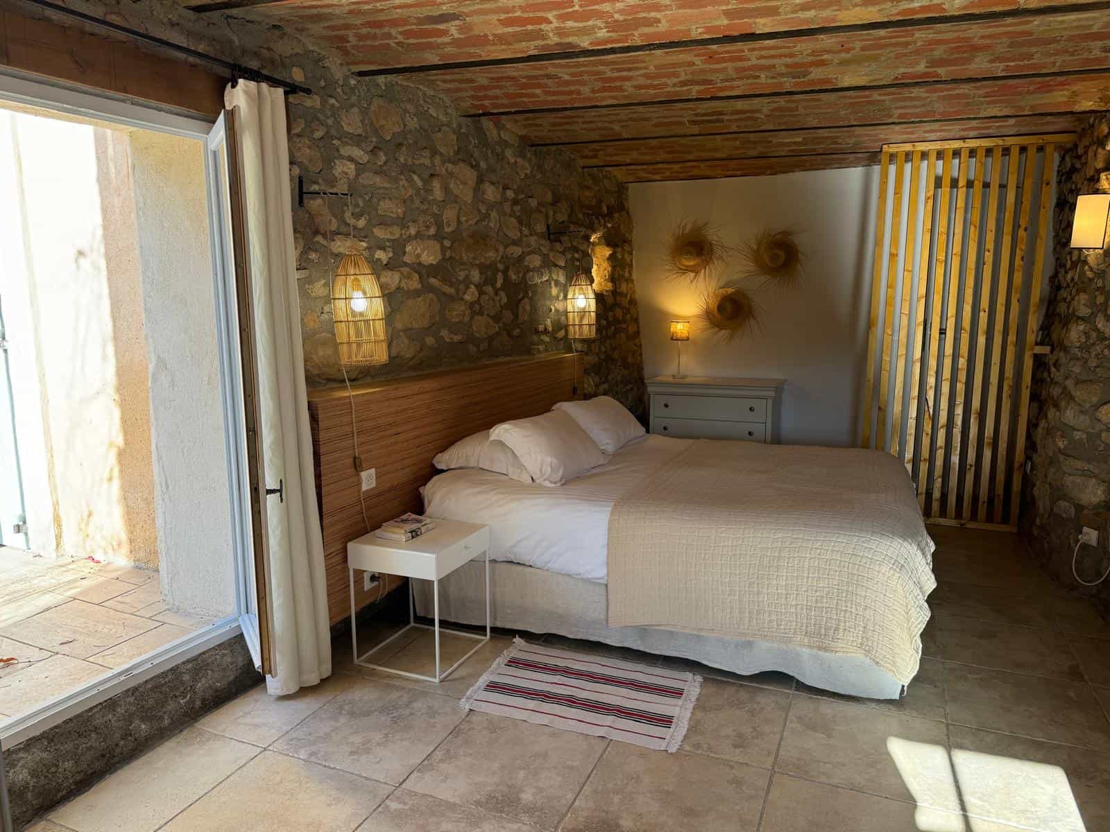 chambre provençale avec des murs en pierres apparentes, lit en 180*200 et salle de bains attenante